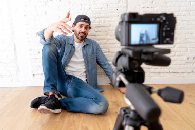 Hippi tarzı video kamera tripod karşı tuğla duvar arka planda internet blog ve blogger kavramı üzerinde rahat kıyafetler genç çekici adam.