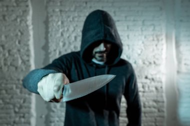 close up of hand holding a knife of dangerous hooded man standing in the dark.  London knife crime concept. clipart