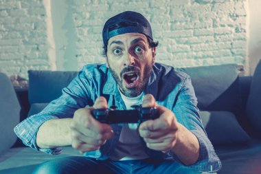 oturma odası kanepe ve video oyunları oyun bağımlılığı kavramında eğleniyor ucube yoğun yüz ifadesi ile uzaktan kumanda joystick kullanarak çalmayı genç heyecanlı latin adam evde oturan