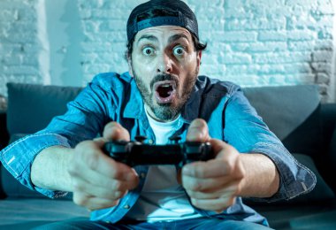 oturma odası kanepe ve video oyunları oyun bağımlılığı kavramında eğleniyor ucube yoğun yüz ifadesi ile uzaktan kumanda joystick kullanarak çalmayı genç heyecanlı latin adam evde oturan