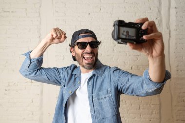 Hippi tarzı modern bir görünüm kendi kendine portre çekim ya da yazmak video internet blog ve blogger kavramında fotoğraf kamera tutarak rahat kıyafetler giymiş genç çekici adam.