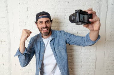Hippi tarzı modern bir görünüm kendi kendine portre çekim ya da yazmak video internet blog ve blogger kavramında fotoğraf kamera tutarak rahat kıyafetler giymiş genç çekici adam.
