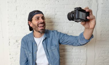 Hippi tarzı modern bir görünüm kendi kendine portre çekim ya da yazmak video internet blog ve blogger kavramında fotoğraf kamera tutarak rahat kıyafetler giymiş genç çekici adam.