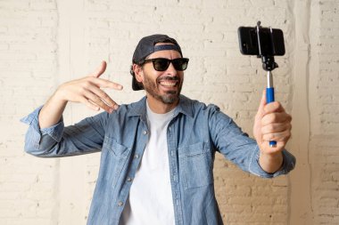 genç çekici adam rahat kıyafetler, şapka selfie sopa cep telefonu kendi kendine portre fotoğraf çekim veya video kaydı tutan hippi tarzı. İnternet blog ve blogger kavramı.
