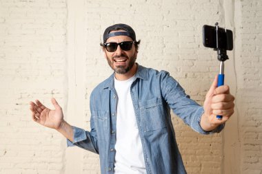 genç çekici adam rahat kıyafetler, şapka selfie sopa cep telefonu kendi kendine portre fotoğraf çekim veya video kaydı tutan hippi tarzı. İnternet blog ve blogger kavramı.