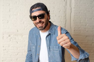 genç çekici hippi, trendy tarzı rahat şapka gayrı giyinme tutum ile mutlu poz serin gülümseyen adam arıyorum. Erkek moda kavramı. Başparmak göstermek yukarıya adam