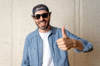 genç çekici hippi, trendy tarzı rahat şapka gayrı giyinme tutum ile mutlu poz serin gülümseyen adam arıyorum. Erkek moda kavramı. Başparmak göstermek yukarıya adam