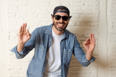 genç çekici hippi, trendy tarzı rahat şapka gayrı giyinme tutum ile mutlu poz serin gülümseyen adam arıyorum. Erkek moda kavramı. Tamam gösterilen adam 