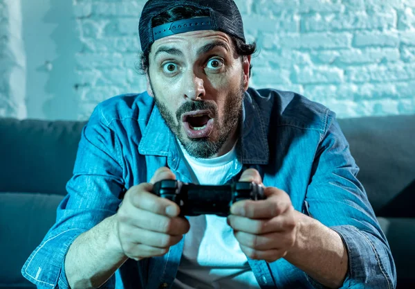 oturma odası kanepe ve video oyunları oyun bağımlılığı kavramında eğleniyor ucube yoğun yüz ifadesi ile uzaktan kumanda joystick kullanarak çalmayı genç heyecanlı latin adam evde oturan