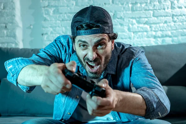 oturma odası kanepe ve video oyunları oyun bağımlılığı kavramında eğleniyor ucube yoğun yüz ifadesi ile uzaktan kumanda joystick kullanarak çalmayı genç heyecanlı latin adam evde oturan