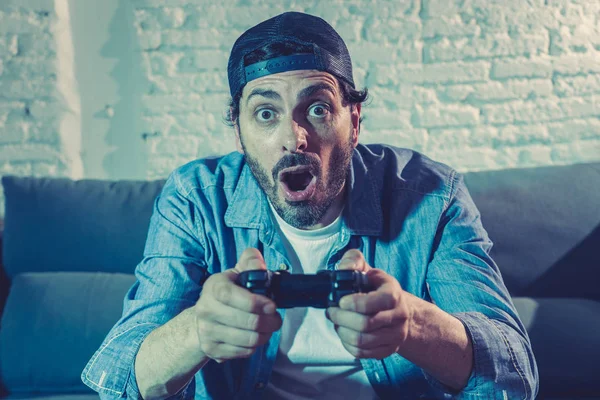 oturma odası kanepe ve video oyunları oyun bağımlılığı kavramında eğleniyor ucube yoğun yüz ifadesi ile uzaktan kumanda joystick kullanarak çalmayı genç heyecanlı latin adam evde oturan