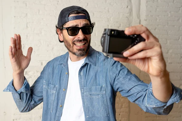 Hippi tarzı modern bir görünüm kendi kendine portre çekim ya da yazmak video internet blog ve blogger kavramında fotoğraf kamera tutarak rahat kıyafetler giymiş genç çekici adam.