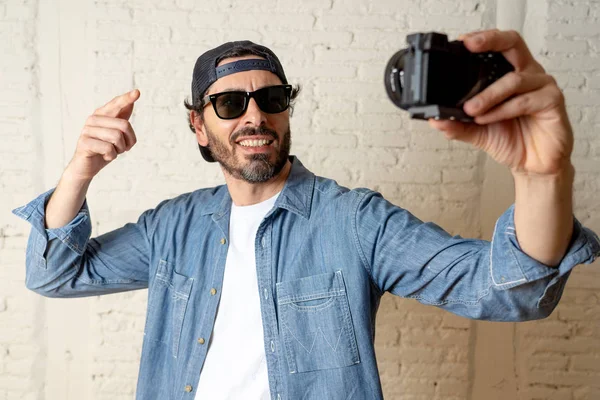 Hippi tarzı modern bir görünüm kendi kendine portre çekim ya da yazmak video internet blog ve blogger kavramında fotoğraf kamera tutarak rahat kıyafetler giymiş genç çekici adam.