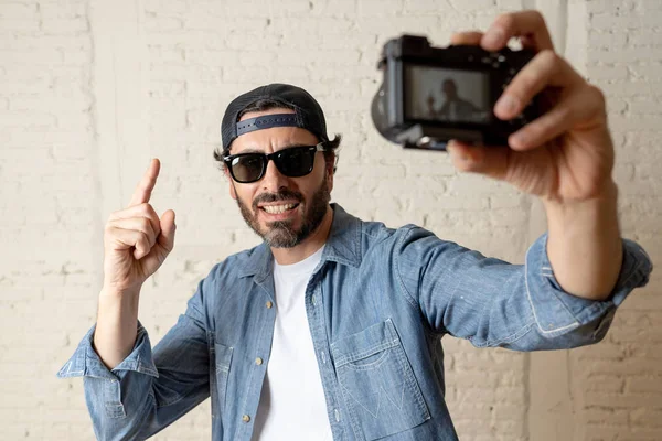 Hippi tarzı modern bir görünüm kendi kendine portre çekim ya da yazmak video internet blog ve blogger kavramında fotoğraf kamera tutarak rahat kıyafetler giymiş genç çekici adam.