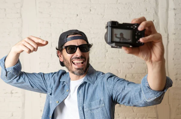 Hippi tarzı modern bir görünüm kendi kendine portre çekim ya da yazmak video internet blog ve blogger kavramında fotoğraf kamera tutarak rahat kıyafetler giymiş genç çekici adam.