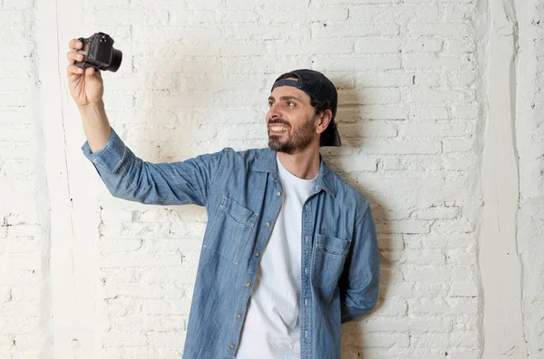 Hippi tarzı modern bir görünüm kendi kendine portre çekim ya da yazmak video internet blog ve blogger kavramında fotoğraf kamera tutarak rahat kıyafetler giymiş genç çekici adam.
