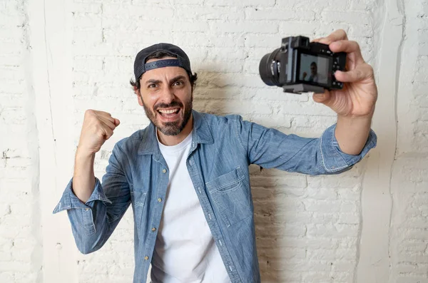 Hippi tarzı modern bir görünüm kendi kendine portre çekim ya da yazmak video internet blog ve blogger kavramında fotoğraf kamera tutarak rahat kıyafetler giymiş genç çekici adam.