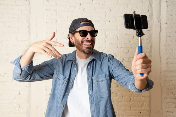 genç çekici adam rahat kıyafetler, şapka selfie sopa cep telefonu kendi kendine portre fotoğraf çekim veya video kaydı tutan hippi tarzı. İnternet blog ve blogger kavramı.