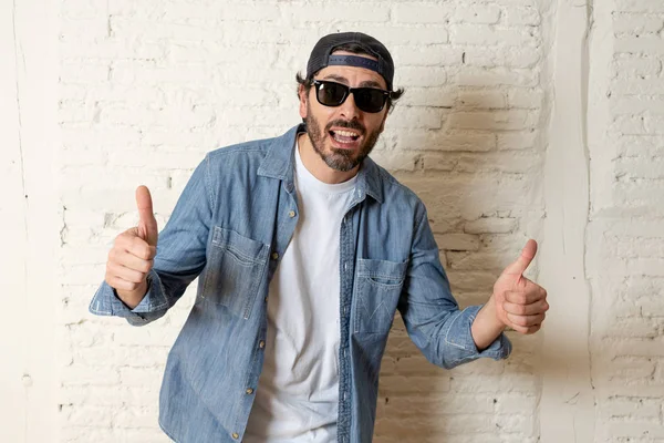 genç çekici hippi, trendy tarzı rahat şapka gayrı giyinme tutum ile mutlu poz serin gülümseyen adam arıyorum. Erkek moda kavramı. Başparmak göstermek yukarıya adam