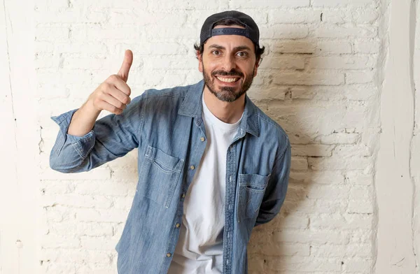 genç çekici hippi, trendy tarzı rahat şapka gayrı giyinme tutum ile mutlu poz serin gülümseyen adam arıyorum. Erkek moda kavramı. Başparmak göstermek yukarıya adam
