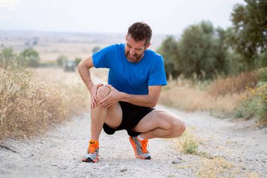 Güçlü atletik bacak kas yaralanması kas asfalt yolda çalışan bir egzersiz eğitim sırasında şikayetinden sonra ağrı diz elleriyle tutan adamla genç spor veya bağ yaralanması kavramı.