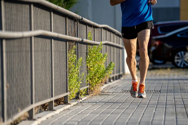 Closeup of sports mans legs running with sport background urban city backdrop in runner fitness concept with copy space