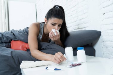 Hasta İspanyol kadın yatakta hasta günde iş termometre diyerek ateş ve vitaminler sıcak su şişesi ve soğuk algınlığı ve grip kavramı içinde doku için sıcaklık kontrol