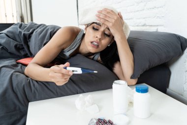 Hasta İspanyol kadın yatakta hasta günde iş termometre diyerek ateş ve vitaminler sıcak su şişesi ve soğuk algınlığı ve grip kavramı içinde doku için sıcaklık kontrol