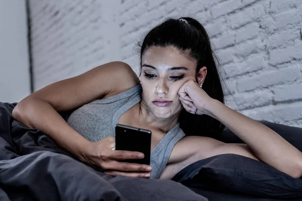 年轻美丽的拉丁女人在床上深夜说话和使用手机无聊和厌倦使用智能手机在互联网通信过度利用概念和智能手机成瘾 — 图库照片