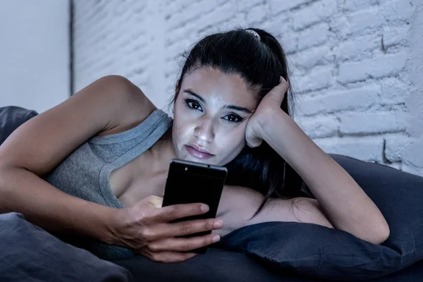 年轻美丽的拉丁女人在床上深夜说话和使用手机无聊和厌倦使用智能手机在互联网通信过度利用概念和智能手机成瘾 — 图库照片