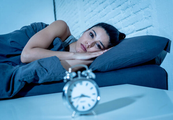 молодая красивая латиноамериканка в спальне лежала в постели поздно ночью пытаясь заснуть страдая бессонницей бессонница или напуганный кошмарами выглядящий грустно обеспокоенный концепцией психического здоровья
