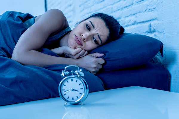 молодая красивая латиноамериканка в спальне лежала в постели поздно ночью пытаясь заснуть страдая бессонницей бессонница или напуганный кошмарами выглядящий грустно обеспокоенный концепцией психического здоровья
