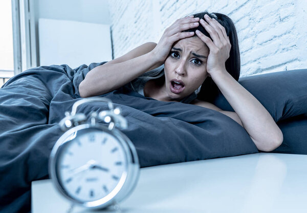 молодая красивая латиноамериканка в спальне лежала в постели поздно ночью пытаясь заснуть страдая бессонницей бессонница или напуганный кошмарами выглядящий грустно обеспокоенный концепцией психического здоровья
