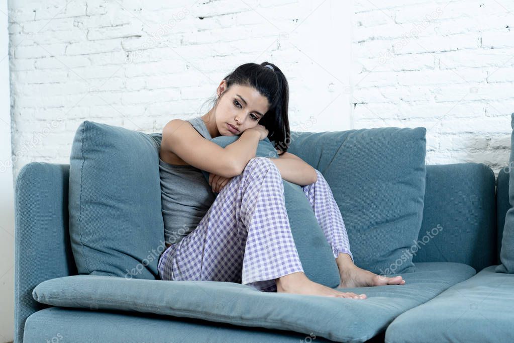 young attractive latin woman lying at home living room couch tired and worried suffering from depression feeling sad lonely and desperate hugging pillow in depressed mental health concept.