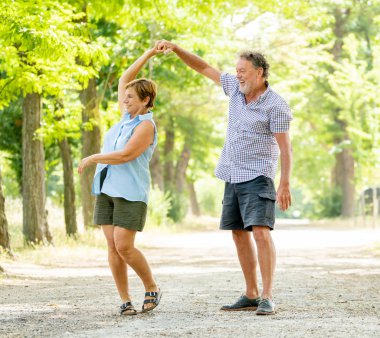 Mutlu üst düzey iki aşk içinde gülümseyen, dans ve parkta having fun.