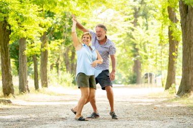 Mutlu üst düzey iki aşk içinde gülümseyen, dans ve parkta having fun.