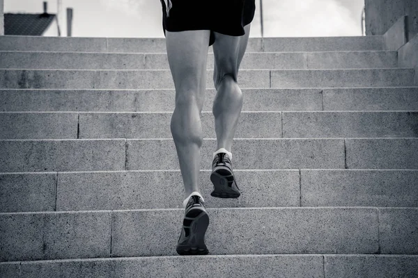 male runner training on stairs in urban city, rear view, monochrome