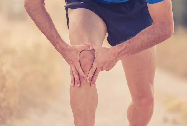 close up of man with strong athletic legs holding knee suffering of muscle injury