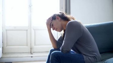 Genç çekici latin kadın evde oturma odası kanepe üzgün yalan yorgun ve ruh sağlığı, sorunları ve kırık kalp kavramı depresyon acı endişeli.