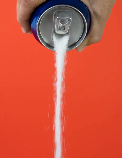 Hand holding a soda can pouring sugar