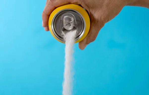 Hand holding a soda can pouring sugar