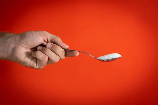 Mano sosteniendo una cuchara llena de azúcar — Foto de Stock