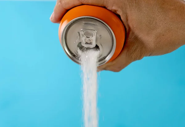 Hand holding a soda can pouring sugar