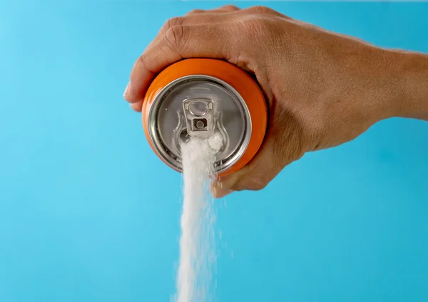 Hand holding a soda can pouring sugar