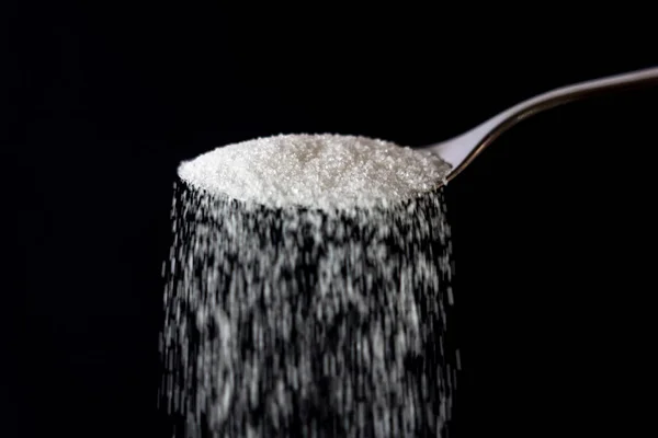 Azúcar que vierte de una cuchara — Foto de Stock