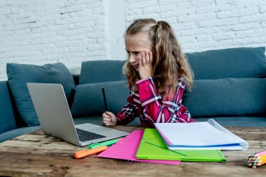 Sevimli İlköğretim öğrenci ile onu laptop evde zor atama yaparken duygu üzgün ve kafa karıştırıcı. Ödev ve çocuk eğitim kavramı.