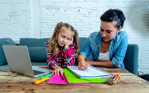 Mother becoming frustrated with daughter while doing homework on sofa at home