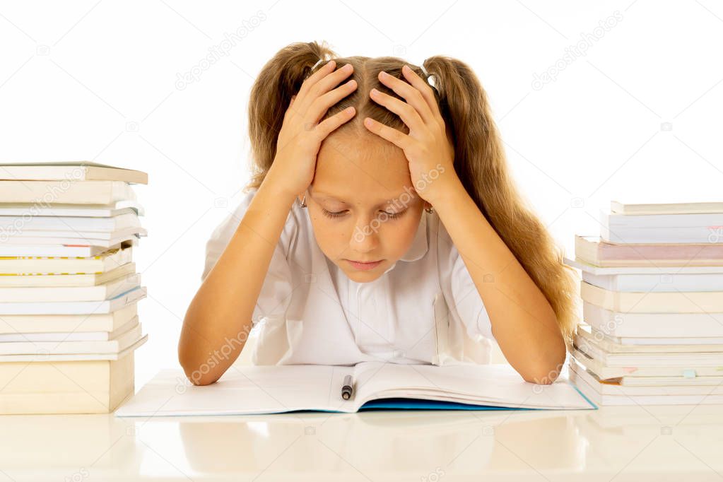 Sad and tired cute schoolgirl sitting in stress while doing homework. overwhelm with too much study and textbooks. Children education academic performance and school systems concept