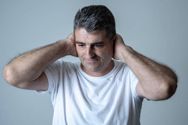 Portrait of an attractive man sad an depressed suffering depression feeling sorrow and pain in human emotions facial expressions and depression concept isolated on grey blue background