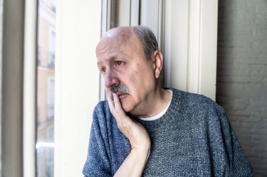 Üst düzey ihtiyar duygu pencereden bakan şaşkın ve yaşlanma emeklilik dul demans ve Alzheimer kavramı evde yalnız depresif.